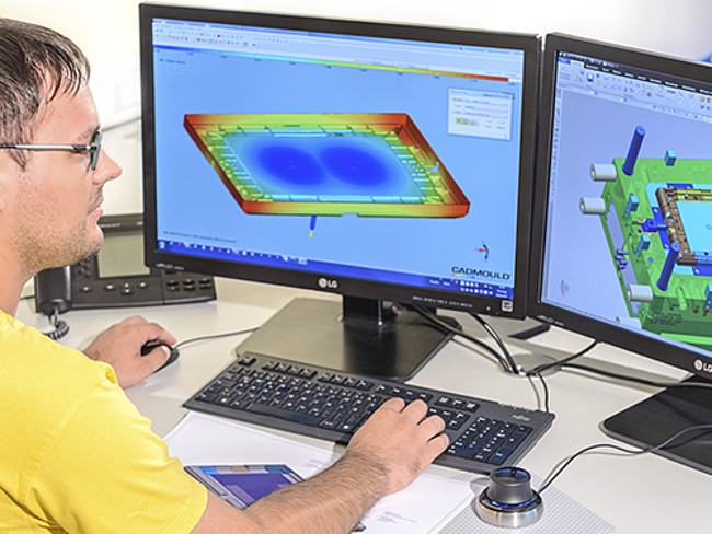 An employee sits at the computer and works on product development
